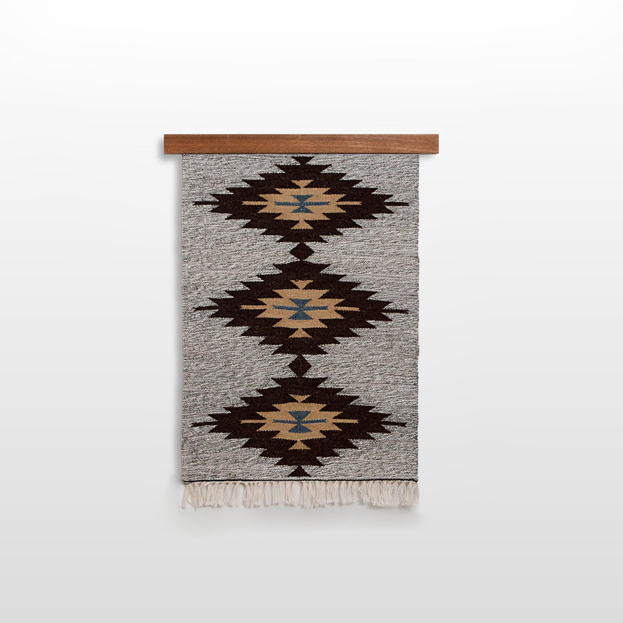 The Handmade in Ukraine Organic 100% Sheep Wool Woven Rug Wall Hanging Decor, featuring geometric patterns, is displayed on a wooden rod against a white wall.