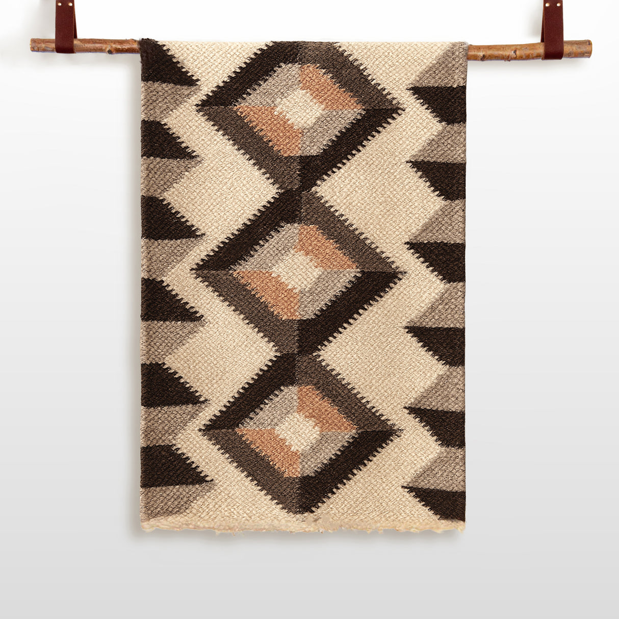 The Svitlo (Bright) Wool Wall Hanging features a beige base with geometric diamond patterns in brown, black, and tan, displayed on a wooden rod—a stunning piece of handcrafted woven wall art.