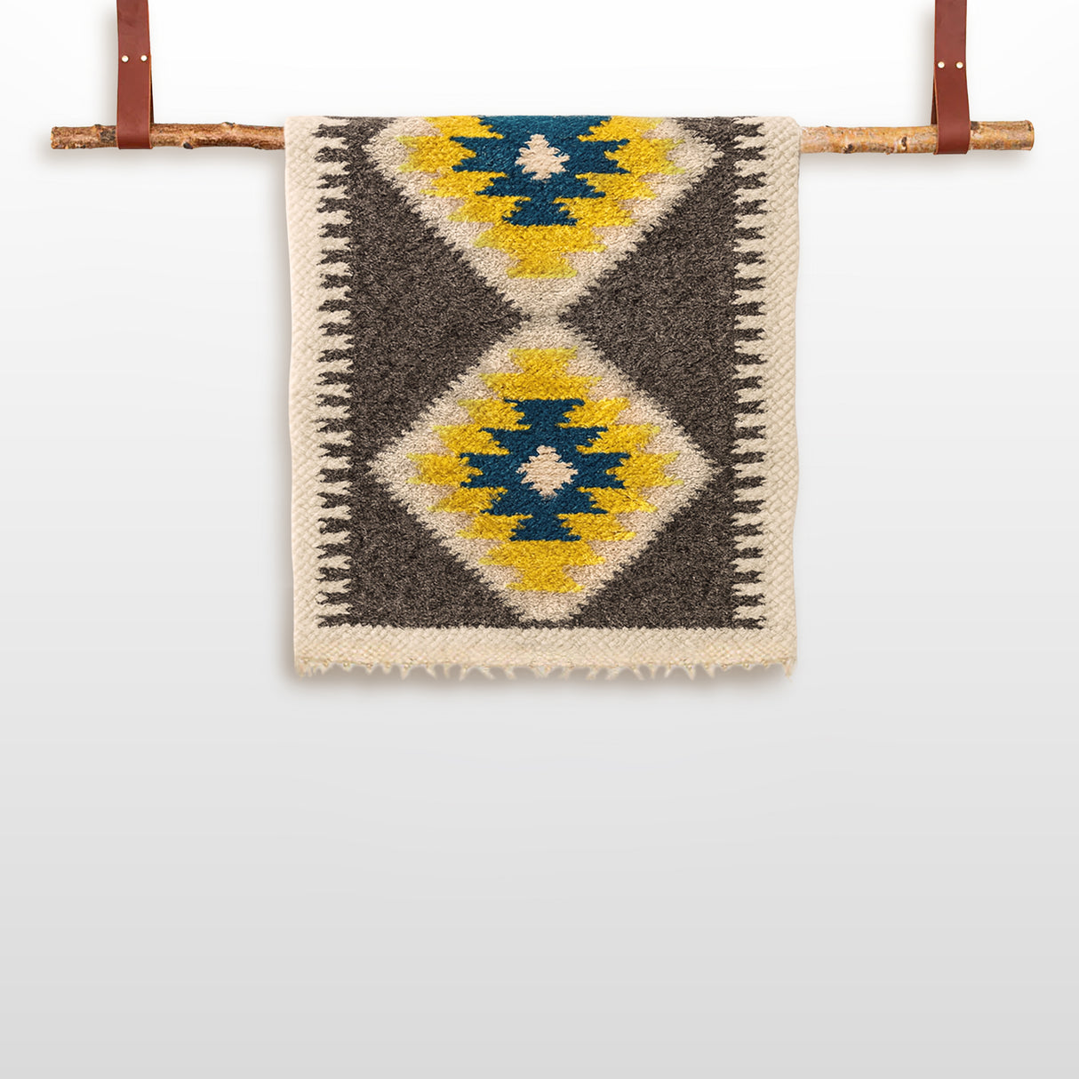 The Organic 100% Sheep Wool Bed Runner from the Carpathian Mountain Collection, a handmade Ukrainian bedspread, features yellow, blue, and black diamond patterns and hangs on a wooden rod with leather straps.