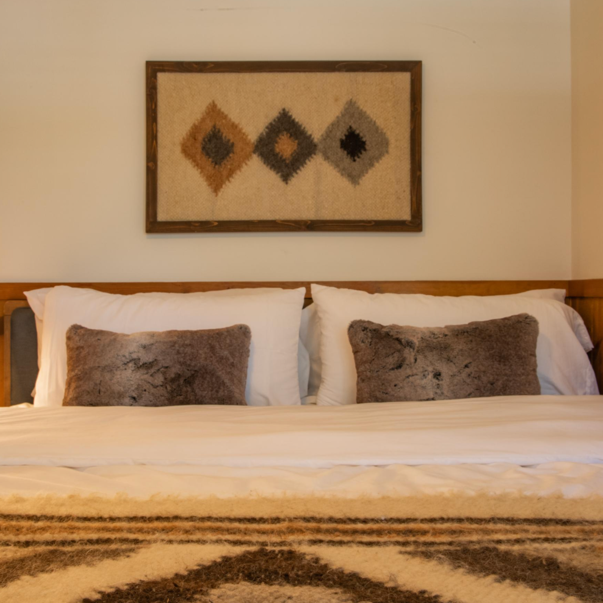 Bed with white linens, two brown pillows, and the Harny (Beautiful) Wool Framed Wall Art above the headboard in a cedar frame.