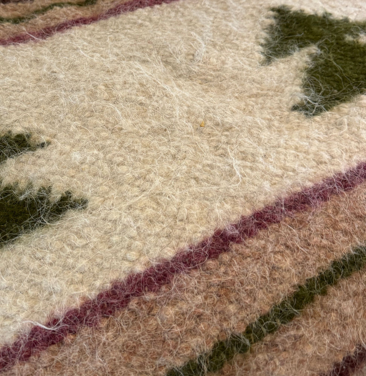 Close-up of the Sosna (Pine) Wool Statement Bed Blanket—handwoven from Carpathian sheep wool, showcasing green and brown geometric patterns on a cream background.