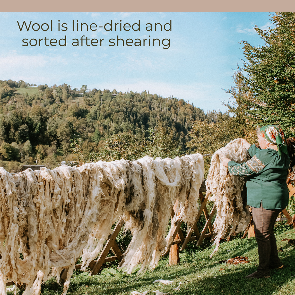 A woman hangs the Zytia (Life) Wool Wall Hanging on a wooden fence in a rural, hilly landscape, celebrating her Ukrainian heritage.