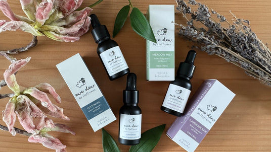 Three Eve Dew skincare serum bottles with boxes, dried leaves, and lavender on a wooden surface.