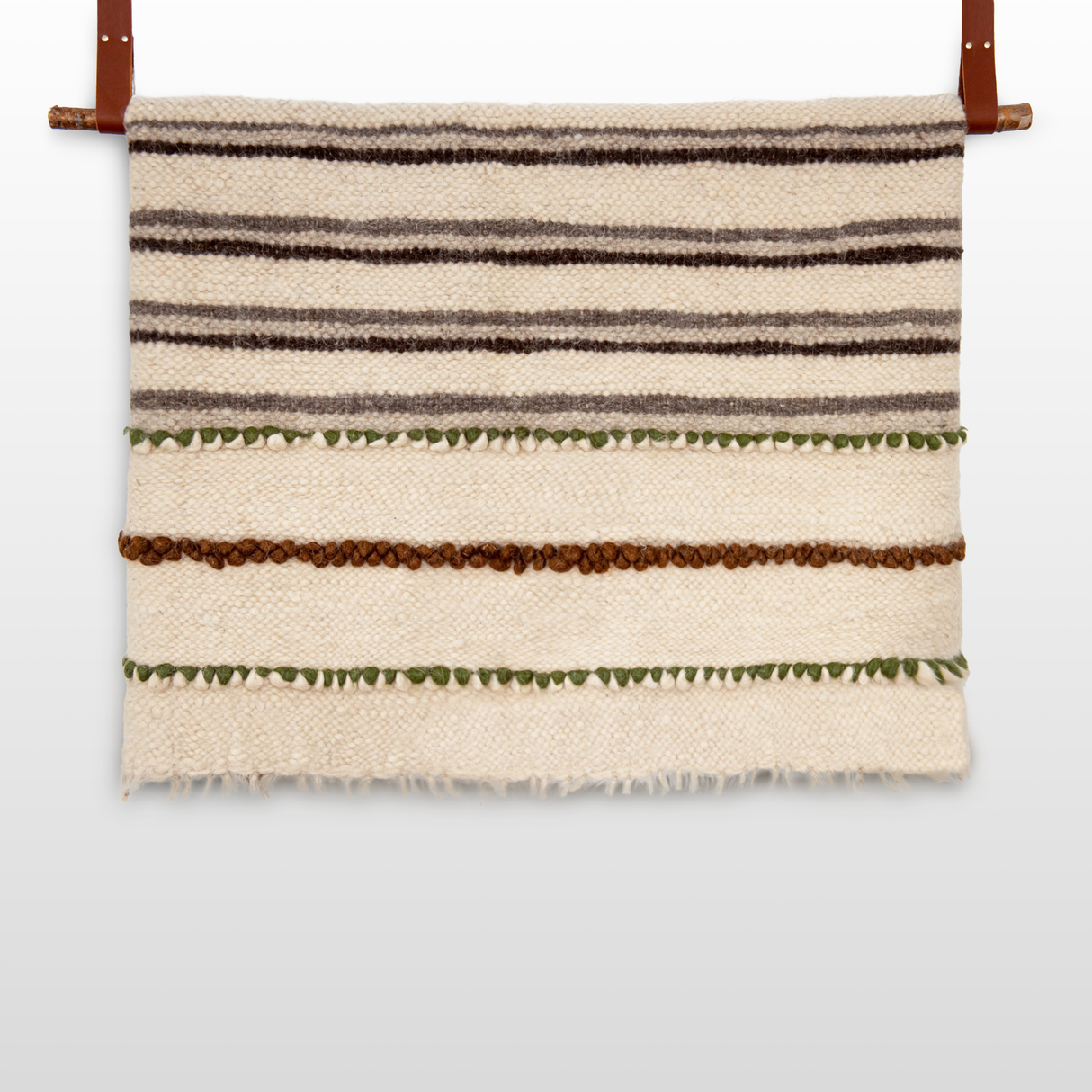 The Faino (Fine) Wool Statement Bed Blanket features horizontal brown, green, and beige stripes and leather straps—handcrafted wool reimagined as striking wall art.