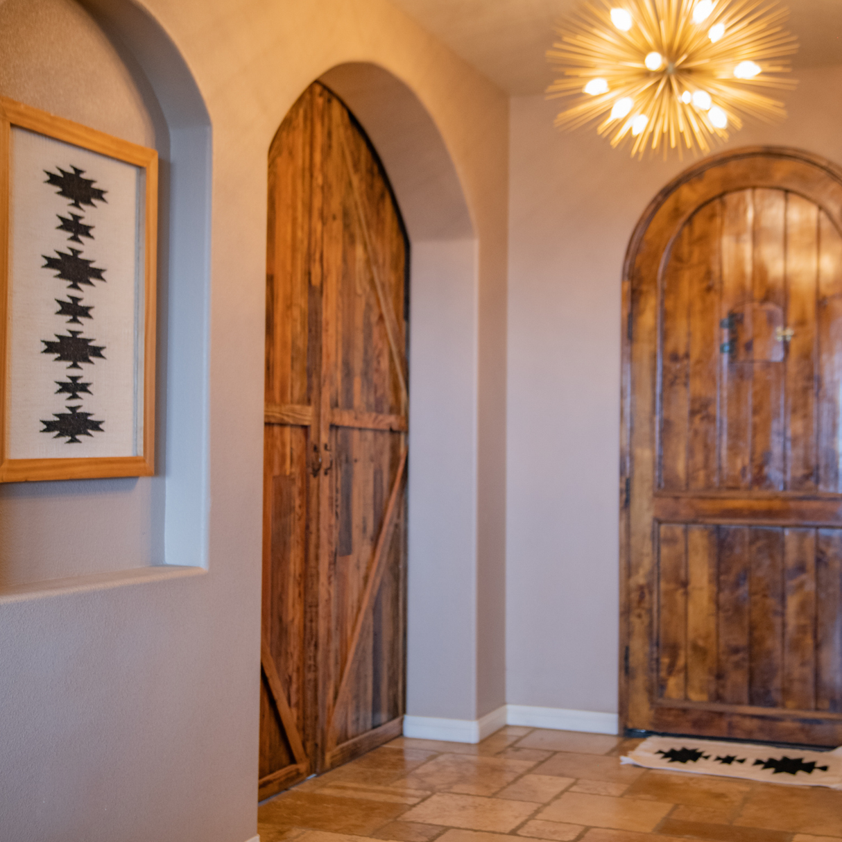 Hallway featuring arched doorways, Western Hemlock wooden doors, geometric art, a modern starburst ceiling light, and the Chysto (Pure) Wool Rug / Wall Hanging with a Wood Rug Hanger ($240 value) as a stylish accent piece.