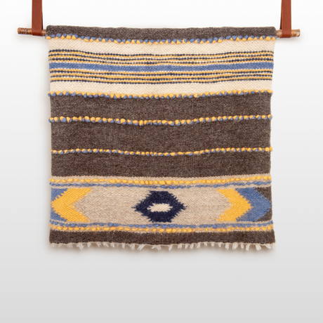 The Zoloty (Golden) Wool Statement Bed Blanket features handcrafted geometric patterns in brown, blue, yellow, and cream, making it a perfect statement piece for your space.