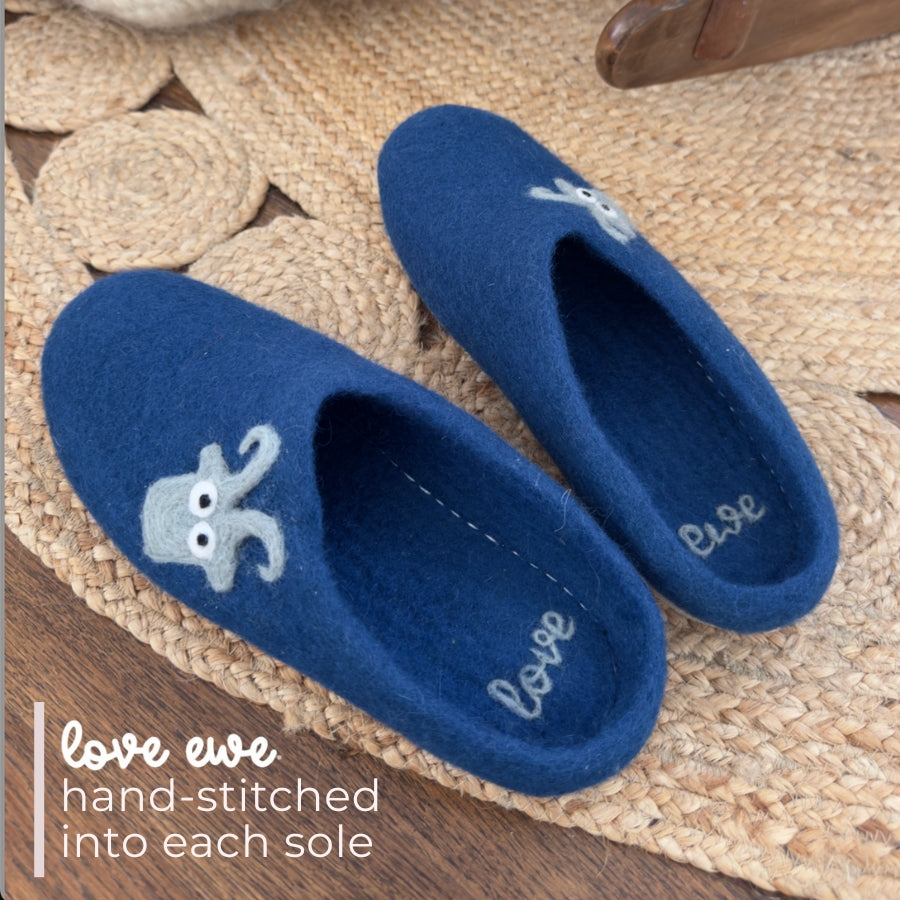Love Ewe Hand-Felted Organic Wool Slippers for Men (Blu-BL), handmade in Nepal, feature a stitched octopus design and “love ewe” on the soles, shown on a woven rug.