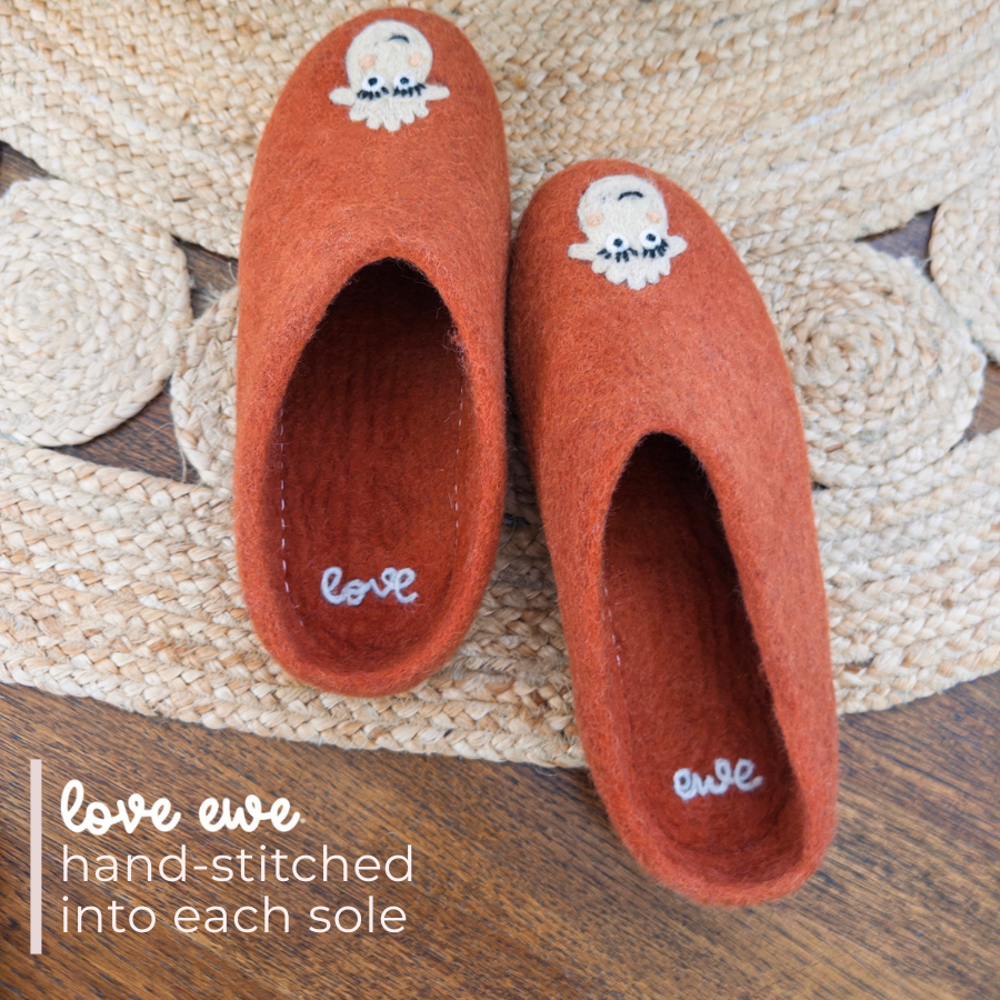 Pair of blush Love Ewe Hand-Felted Organic Wool Slippers for Women (Blush-OG), made from organic New Zealand wool with embroidered sheep and "love ewe" hand-stitched inside each sole, shown on a woven mat.