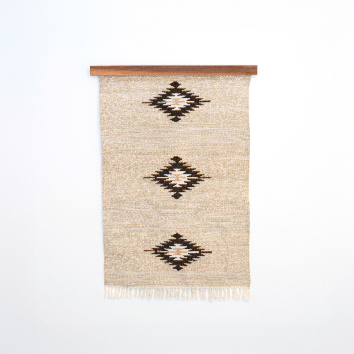 Chitki (Crisp) Wool Rug / Wall Hanging ($240) features a beige base with three black diamond patterns and comes with a wood hanger, crafted in an eco-friendly mill for a natural, artisan touch.