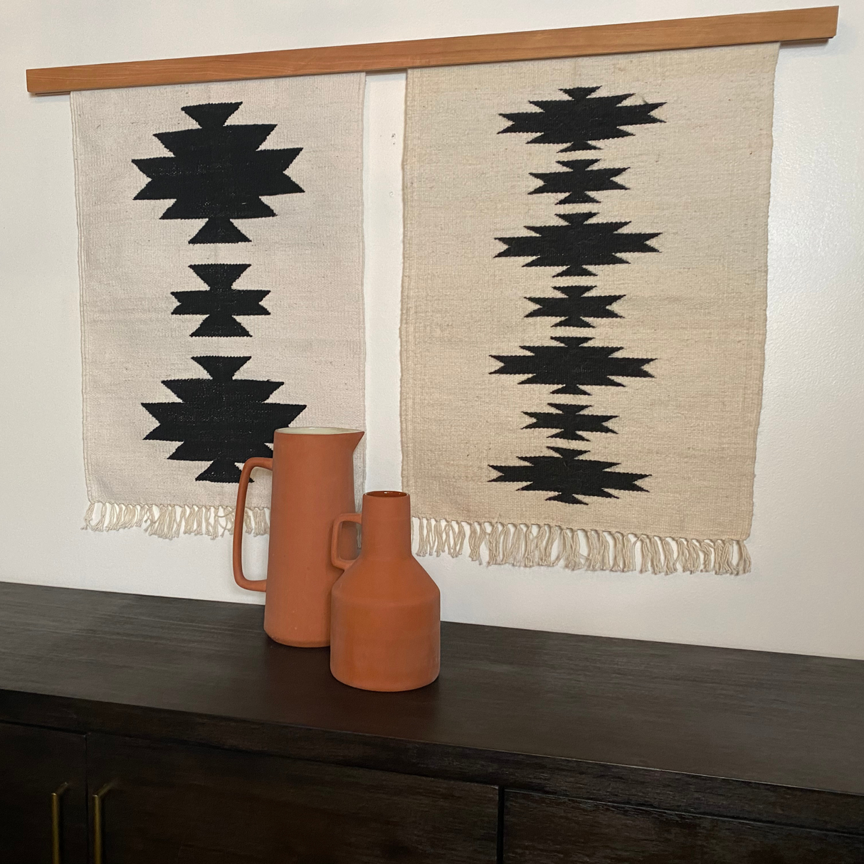 The Chysto (Pure) Wool Rug / Wall Hanging Duo with a wood rug hanger ($465 value) adds eco-friendly style to your space, showcasing sustainable home decor with bold black geometric patterns.
