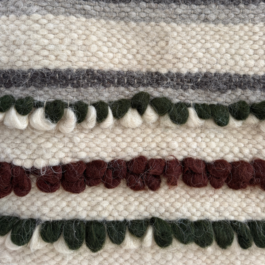 Close-up of the Faino (Fine) Wool Statement Throw/Baby Blanket, showcasing handcrafted cream, green, maroon, and gray textured stripes and looped details.