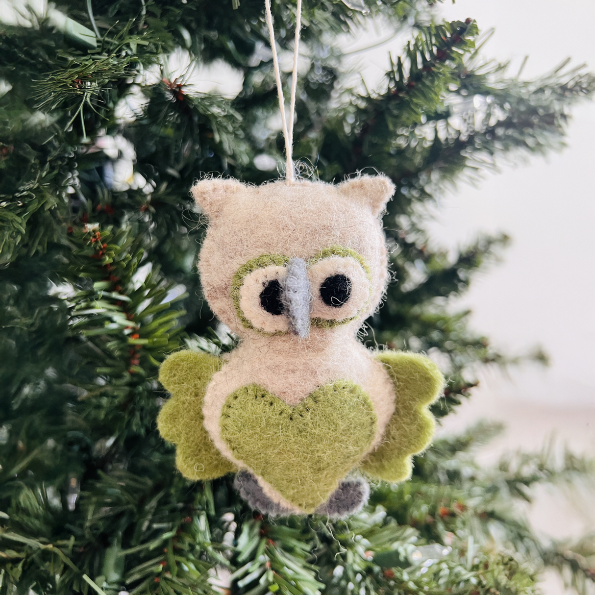 The Hand-Stitched Felted Owl Ornament features green wings and a heart, perfect for hanging on your Christmas tree. This cozy wool ornament adds charm to your holiday decor and makes a great gift for owl lovers.
