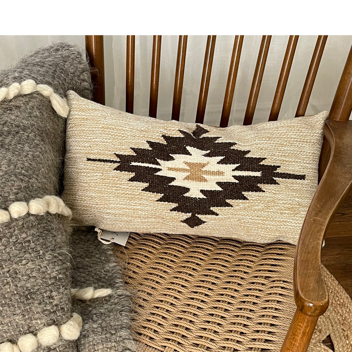 Handwoven Chitki (Crisp) Pillow with a geometric pattern on a woven seat, paired with a chunky knit gray blanket.