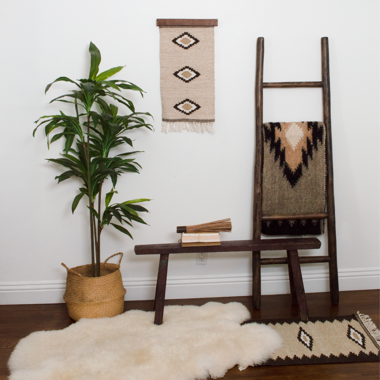Cozy room with a potted plant, wooden bench, wall art, a ladder with blankets, and a soft Heredij (Heritage) Wool Rug / Wall Hanging.