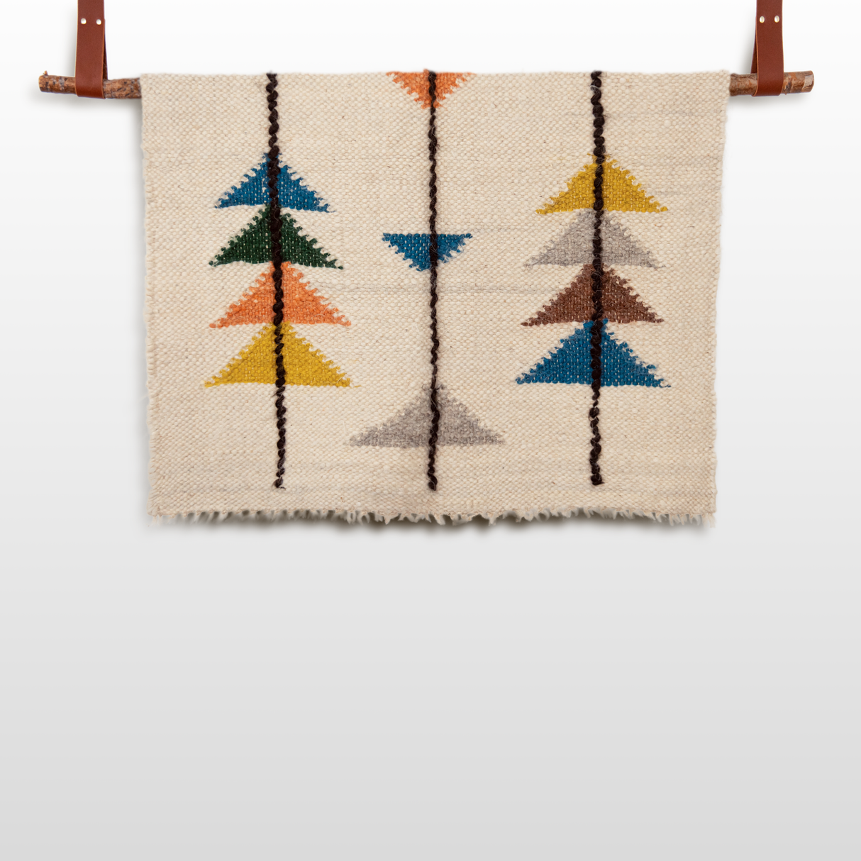 The Lis (Forest) Wool Statement Throw/Baby Blanket showcases colorful geometric arrow patterns inspired by statement blankets, and can be hung as wall art using a wooden rod with leather straps.