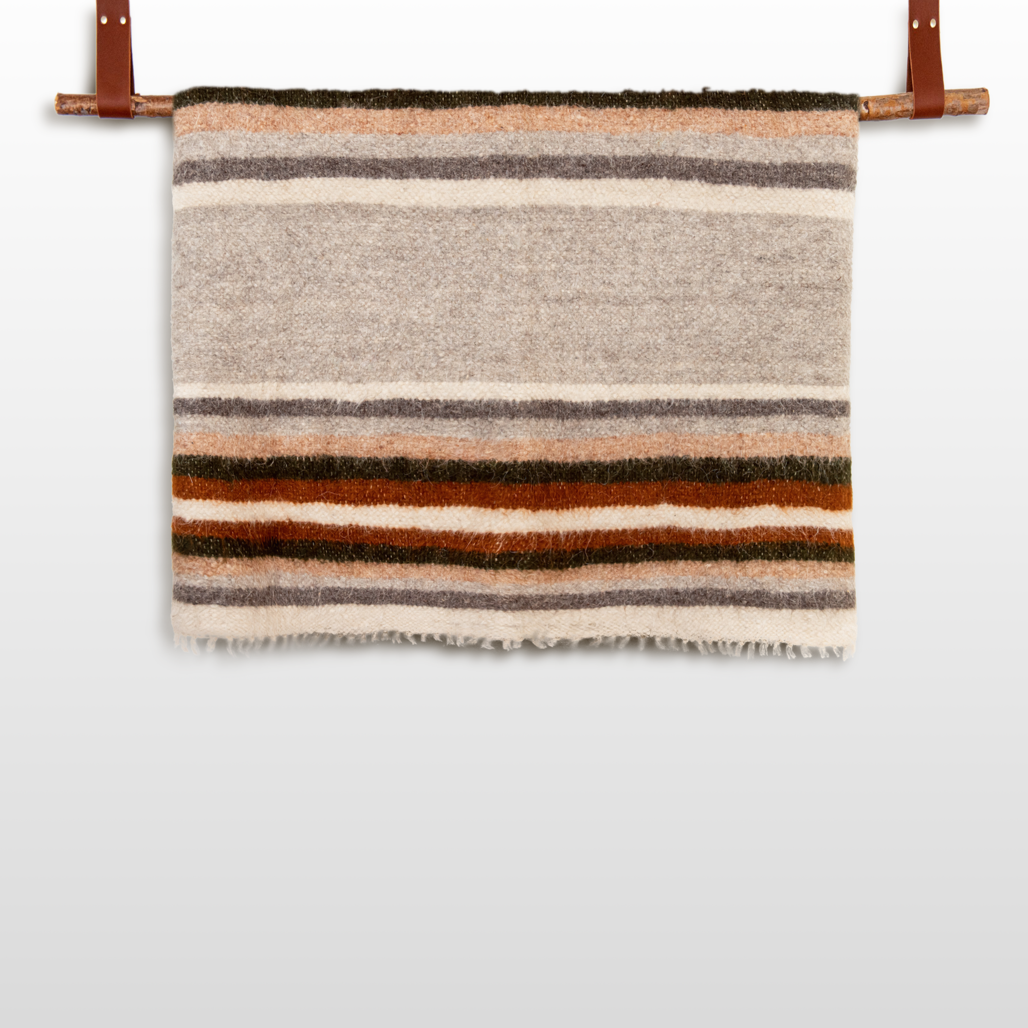 The Mudry (Wise) Wool Statement Baby Blanket, featuring brown, gray, orange, and cream stripes, hangs on a rod with leather straps.