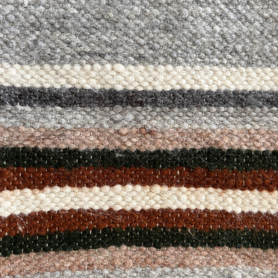 Close-up of Mudry (Wise) Wool Statement Baby Blanket, featuring woven horizontal stripes in gray, cream, brown, black, and dark green—ideal as a cozy statement throw.