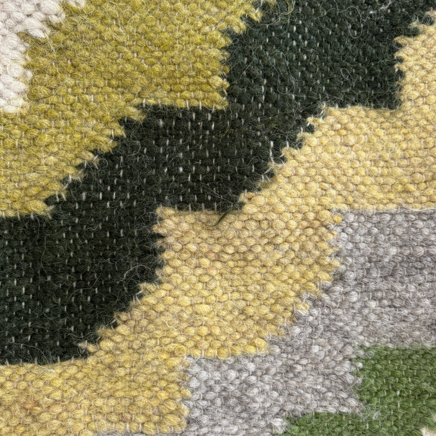 Close-up of the Sontse (Sun) Wool Statement Throw / Baby Blanket, highlighting its handcrafted textured weave with zigzag patterns in green, yellow, and gray.