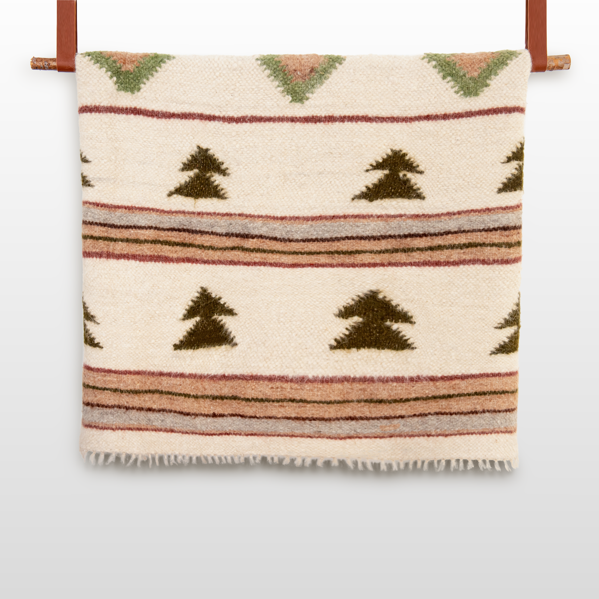 The Sosna (Pine) Wool Statement Bed Blanket features green, brown, and pink geometric patterns and hangs on a wooden rod—perfect for adding warmth and style to your mountain cabin.
