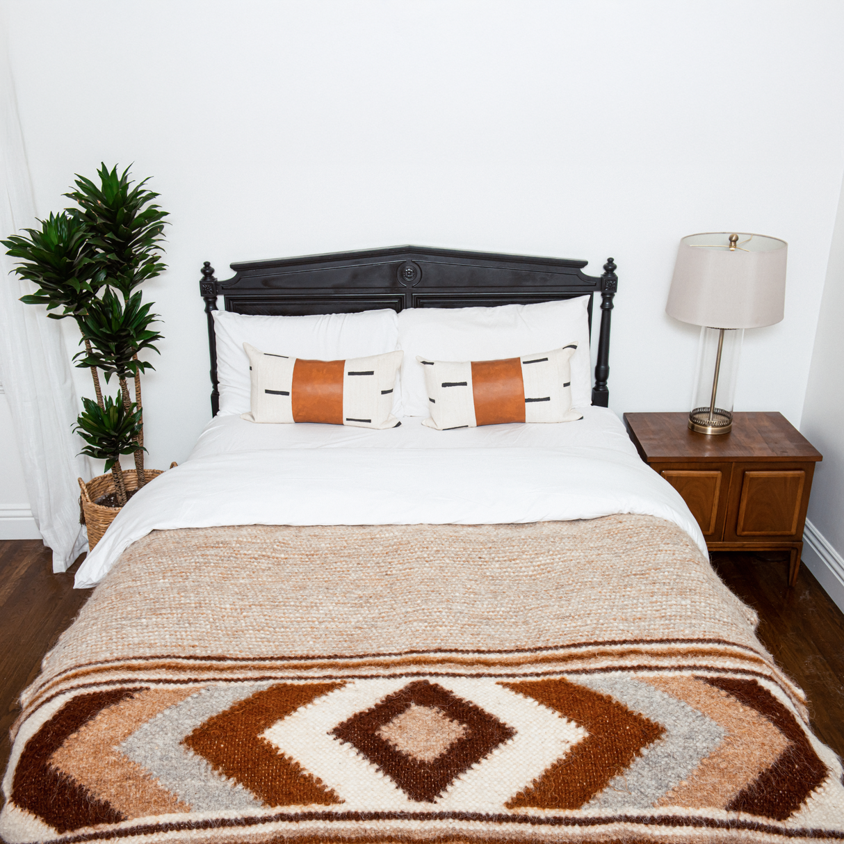A bed with pillows, a lamp, and the Tkach (Weaver) Wool Statement Bed Blanket adds cozy charm to the room.