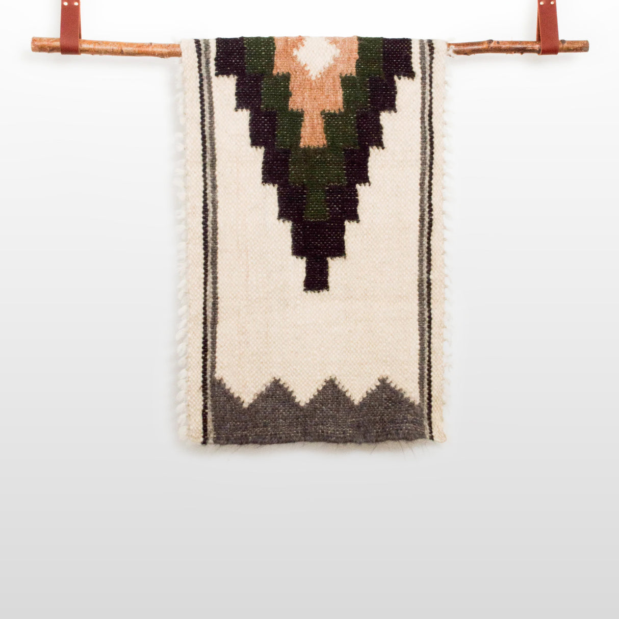 The Myr (Peace) Wool Bed / Couch Runner features a handcrafted wool textile with a rhombus-dot design, hanging from a wooden rod and displayed against a plain white background.