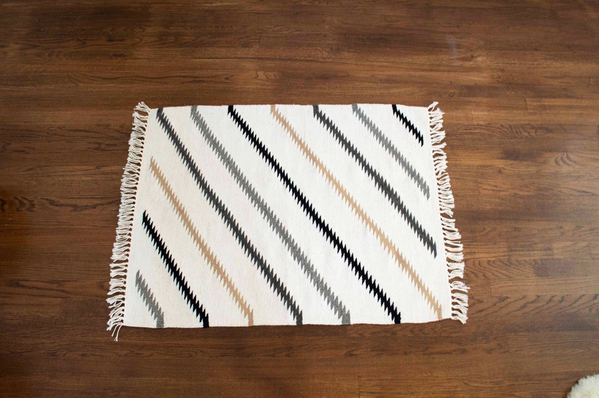 The Handmade in Ukraine Organic Natural 100% Sheep Wool Woven Rug features diagonal black, beige, and gray zigzag stripes—ideal for eco-friendly decor as a small rug or wall hanging.
