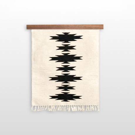 The Chysto (Pure) Wool Rug / Wall Hanging, crafted from Carpathian sheep wool with a black geometric zigzag and fringed edges, is displayed on a hemlock wood rug hanger ($240 value).