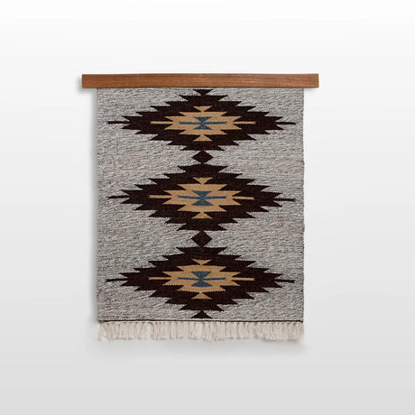 Handmade in Ukraine, this wall hanging is woven from 100% organic sheep wool and features three diamond patterns in brown, gold, and blue with fringe at the bottom.