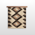 The Svitlo (Bright) Wool Wall Hanging features geometric patterns in earth tones, crafted from organic Carpathian wool, and is displayed hanging on a wooden rod against a white background.