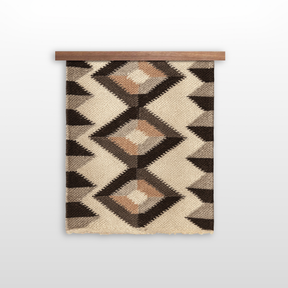 The Svitlo (Bright) Wool Wall Hanging features geometric patterns in earth tones, crafted from organic Carpathian wool, and is displayed hanging on a wooden rod against a white background.