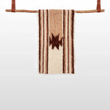 The Opora (Pillar) Wool Bed/Couch Runner, handwoven with brown stripes and a central star plus subtle Carpathian motifs, hangs on a wooden rod with leather straps.