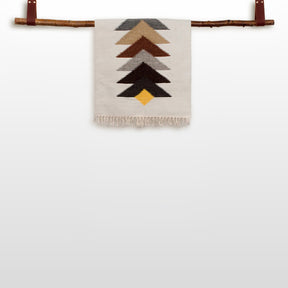 The Strilka (Arrow) Wool Rug / Wall Hanging features woven chevron V shapes in yellow, brown, and gray, creating a vibrant design displayed on a wooden rod.