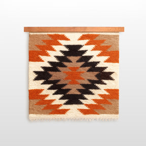 The Zirka (Star) Wool Wall Hanging features handcrafted geometric patterns in black, white, orange, and brown on a wooden rod, inspired by the Ukrainian star motif.
