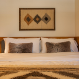 Bed with white linens, two brown pillows, and the Harny (Beautiful) Wool Framed Wall Art above the headboard in a cedar frame.