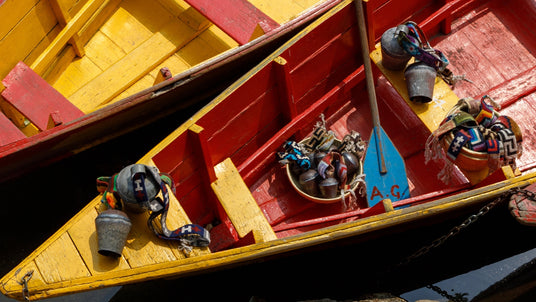 Three colorful wooden boats with traditional hats and water jugs arranged inside, viewed from above.