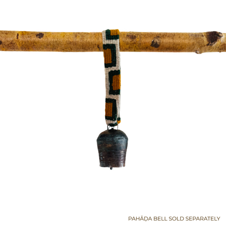 A metal bell with a Medium Strap for Hanging Vintage Bells hangs from a wooden branch; text reads "PAHĀḌA BELL SOLD SEPARATELY.