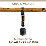 A Medium Straps for Hanging Vintage Bells, artisan-made and sized 1.5" wide by 20-30" long with a metal bell, hangs from a branch.