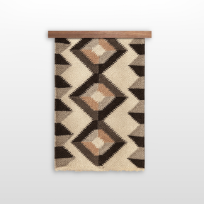 The Svitlo (Bright) Wool Wall Hanging features a geometric pattern in neutral tones, crafted from organic Carpathian wool and displayed on a wooden rod against a white background.