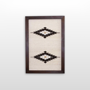 Wool Rug Framed Wall Art, handwoven from Carpathian wool, showcases two black and white geometric diamond patterns on a cream background—an elegant and sustainable home decor accent.