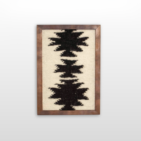 The Chysto (Pure) Wool Framed Wall Art showcases black geometric patterns on a cream wool background, handwoven and inspired by traditional Carpathian wall hanging techniques.