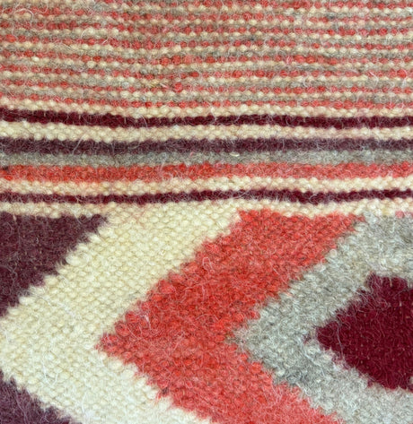 Close-up of the Tkach (Weaver) Wool Statement Bed Blanket, showcasing handwoven red, cream, and maroon geometric patterns with textured fibers.