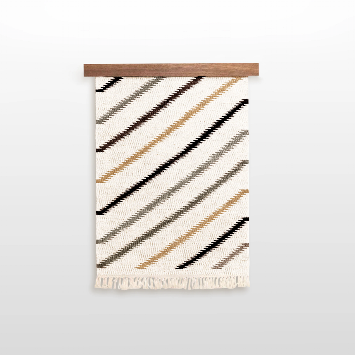 The Promin (Beam) Wool Rug / Wall Hanging, featuring diagonal brown, tan, and black stripes with fringe, comes with a Wood Rug Hanger ($240 value)—a distinctive gallery wall art piece for your space.