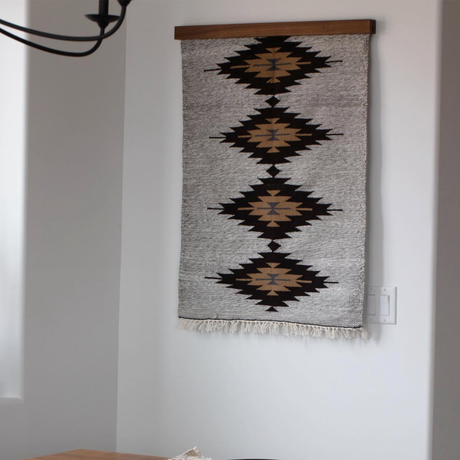 The Smilyv (Bold) Wool Rug / Wall Hanging features a geometric diamond pattern in black and brown on a light background, adding modern, neutral style as a striking accent to any room.