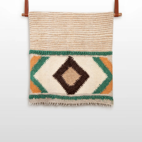 The Tkach (Weaver) Wool Statement Bed Blanket features geometric green, brown, and yellow patterns on beige organic Carpathian wool—a handwoven, handcrafted piece perfect for adding style to any space.