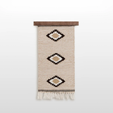 Handmade in Ukraine, this organic 100% sheep wool woven wall hanging decor features three geometric diamond patterns and fringe, crafted by artisans and displayed on a wooden rod.