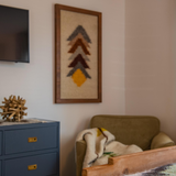 Cozy corner with armchair, Strilka (Arrow) Wool Framed Wall Art, a blue cabinet, and part of a wooden table in view.