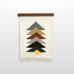 The Strilka (Arrow) Wool Rug / Wall Hanging is handwoven from organic Carpathian wool, featuring stacked colored chevrons and fringe, and displayed on a wooden rod against a white background.
