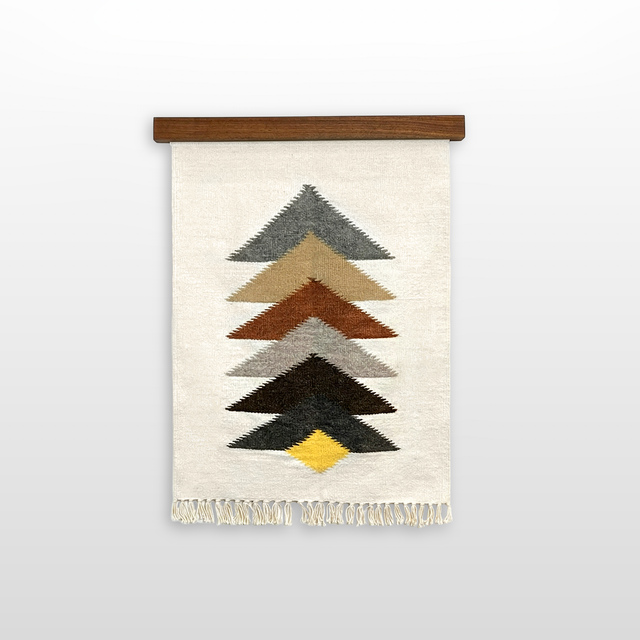 The Strilka (Arrow) Wool Rug / Wall Hanging is handwoven from organic Carpathian wool, featuring stacked colored chevrons and fringe, and displayed on a wooden rod against a white background.