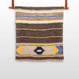The Zoloty (Golden) Wool Statement Bed Blanket features geometric patterns in brown, white, yellow, and blue, inspired by Ukrainian artisan designs.
