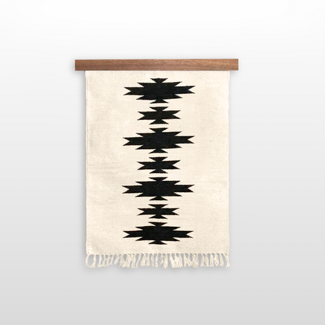 The Chysto (Pure) Wool Rug / Wall Hanging, handwoven from Carpathian sheep wool with black geometric patterns and fringes, comes mounted on a hemlock wood rug hanger ($240 value).